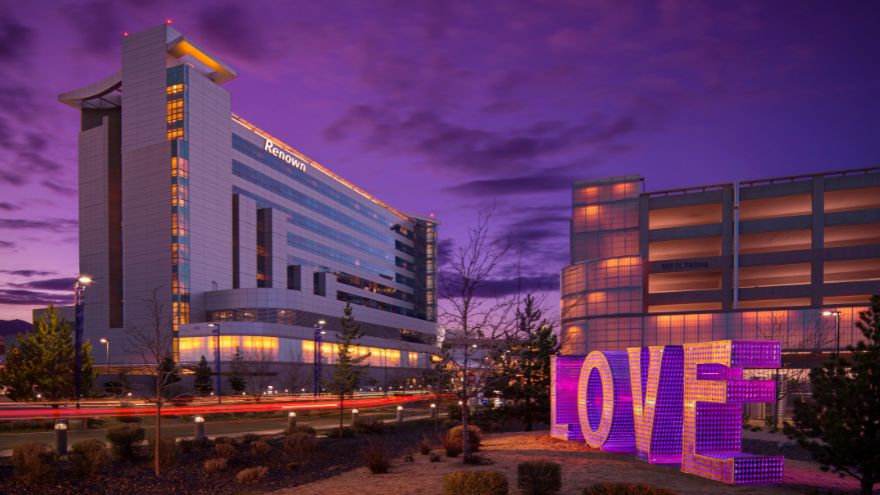 Renown Regional Medical Center stands tall with a purple background and illuminate LOVE sign in the forefront